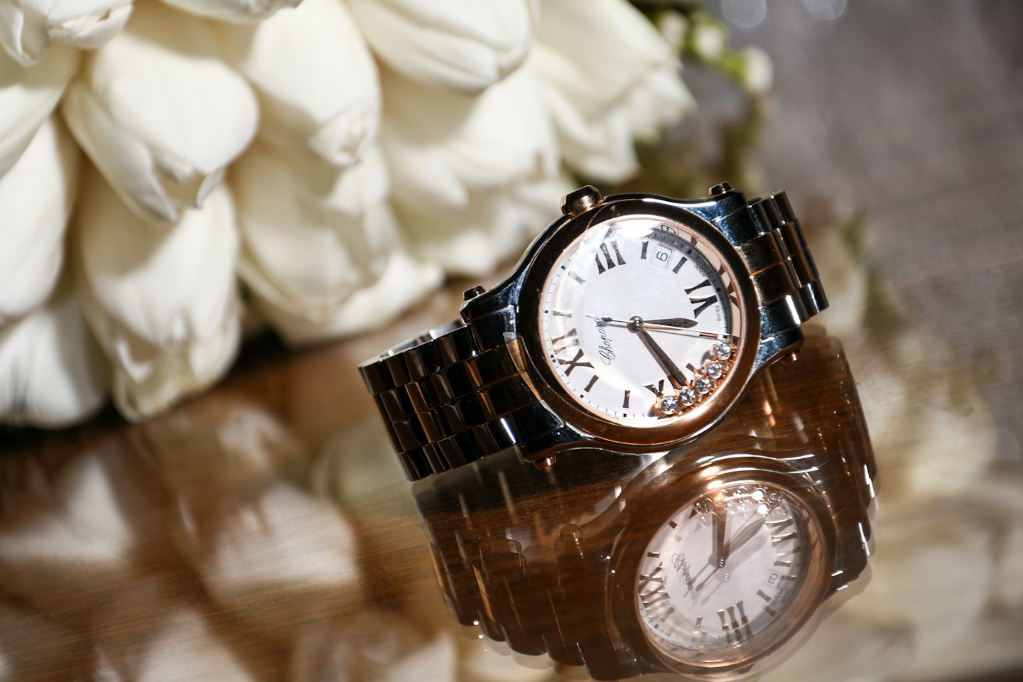 Luxury wristwatch with Roman numerals resting on a reflective surface.