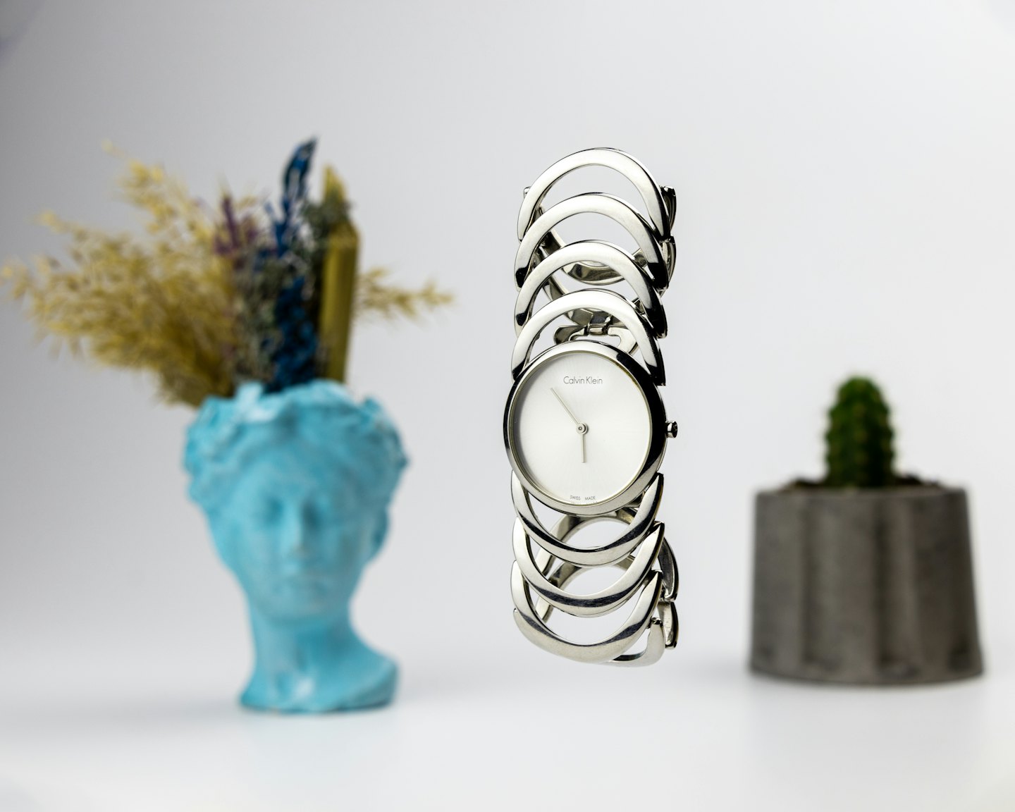 Silver women's watch with white face on linked bracelet.