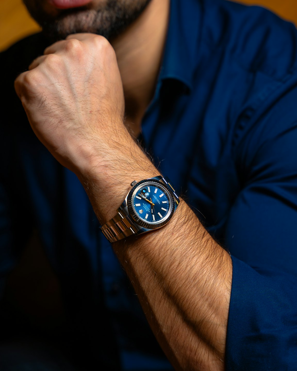 Man wearing a luxury wristwatch with a blue dial.
