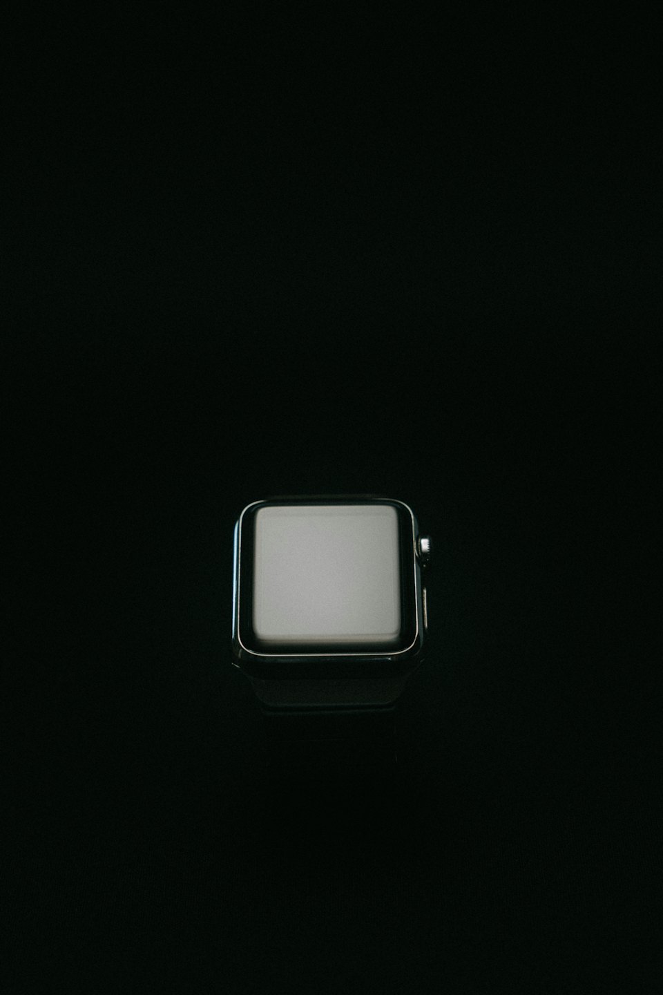Silver smartwatch with a bright blank screen on a dark background.