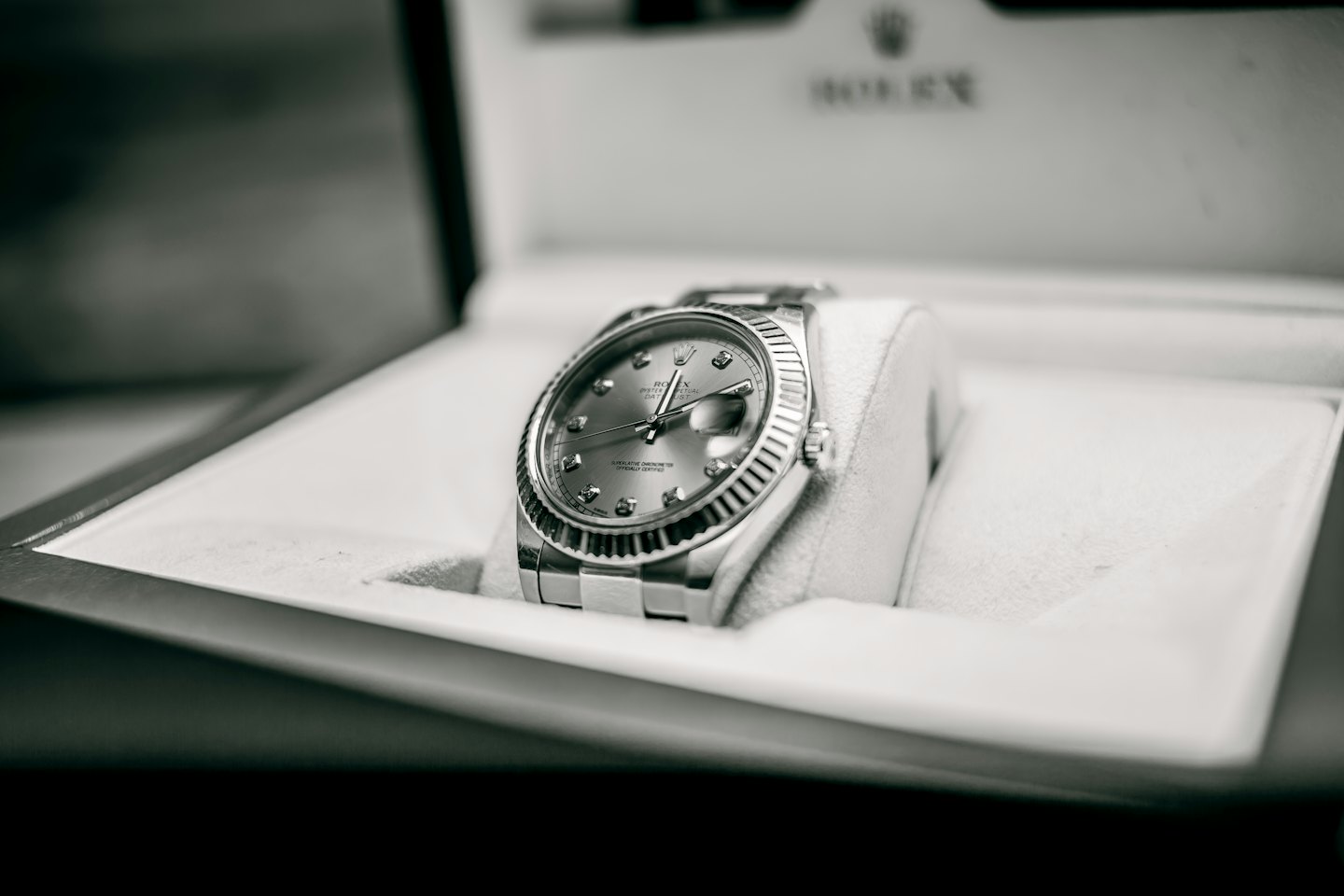 A luxury wristwatch rests on a cushion inside its box.
